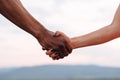 Close-up of mixed race couple holding hands on the misty mountain background. Symbolic photo Royalty Free Stock Photo