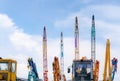 Close-up mobile crane, yellow bulldozer, and blue backhoe parked at second-hand machinery auction yard against blue sky. Heavy