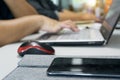 Close up mobile phone on desk with workers typing on laptop keyboard. Focus on cell phone with blurred worker in background Royalty Free Stock Photo