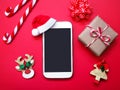 Close up mobile phone with santa claus hat and Christmas ornament on re background Royalty Free Stock Photo