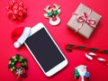 Close up mobile phone with santa claus hat and Christmas ornament on re background Royalty Free Stock Photo