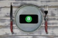 Close up of mobile phone screen with logo lettering of food delivery service grabfood on wood table with dish and cutlery