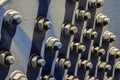 A close-up of a mock of large hex nuts with a washer secured by threaded studs to iron surface. Long, thick shadows