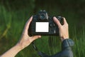 Close-up Mock-up of a professional photo-video camera in the hands of a girl. Against the background of green nature Royalty Free Stock Photo