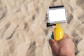 Close-up, Mockup of an action camera in a man& x27;s hand. Beach sand in the background