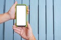 Close-up, Mockup of a smartphone in the hands of a man against the background of a gray rhythmic wooden wall