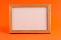 Close up of mockup template white frame with wooden borders on orange blurred background and copy space. Holiday autumn concept