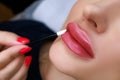 close-up of the model's lips with permanent make-up, the master wipes the model's lips with a cotton swab