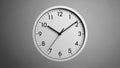 Close-up of modern analog wall clock with white frame and black hands on gray background Royalty Free Stock Photo