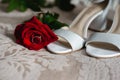 Close up of modern a beautiful, stylish wedding engagement ring, red roze and female shoes.