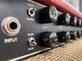 Close-up modern black volume knob of the boutique clean guitar amplifier with blurred black control panel and red leather cover. Royalty Free Stock Photo