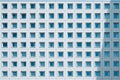 Close Up of a Modern Building Facade with Numerous Square Windows and Blue Curtains, Showing a Repetitive Geometric Pattern Royalty Free Stock Photo