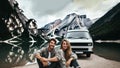 close up of a modern camper van parked on the shore of a mountain lake with a couple enjoying the scenery Royalty Free Stock Photo