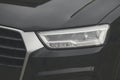 Close-Up of Modern Car Headlight on Glossy Black Vehicle Front with Sleek Design