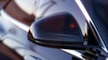 Close-up of a modern car side mirror reflecting light. The sleek design features a glossy black finish and sharp Royalty Free Stock Photo