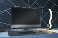 Close up of modern designer desktop with empty black computer monitor, various items and blue wall. Mock up