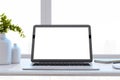 Close up of designer office desktop with white mock up laptop computer screen, decorative vase with plant, other objects Royalty Free Stock Photo