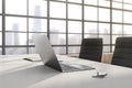 Close up of modern designer office interior with laptop, smartphone, book and window with city view.