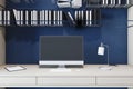 Close up of modern designer workplace with empty computer screen, bookshelves, supplies and dark blue wall background. Mock up, 3D Royalty Free Stock Photo