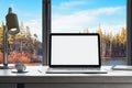 Close up of modern designer workplace in modern office interior with blank white mock up laptop computer screen, window with