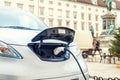 Close-up modern electric car pugged with fast charger at charging station in center of old European city. Ecol friendly green Royalty Free Stock Photo