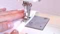 Close-up of a modern electric sewing machine sewing together a piece of textile. The dressmaker works on a sewing