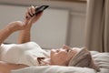 Happy senior woman relax in bed using cellphone at home Royalty Free Stock Photo