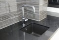 A close-up on a modern kitchen tiled up with gray ceramic wall tile with a curved line design black kitchen countertop square