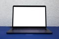 Close-up of modern laptop with empty mockup, on phantom blue desk, background of white textured wall.