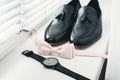 Close up of modern man accessories. beige bow tie, black leather shoes, belt and watch Royalty Free Stock Photo