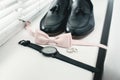 Close up of modern man accessories. beige bow tie, black leather shoes, belt and watch Royalty Free Stock Photo