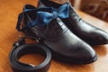 Close up of modern man accessories. Blue bow tie, leather shoes, and belt. Royalty Free Stock Photo