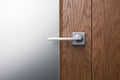 Close - up of a modern metal handle on a dark wooden door Royalty Free Stock Photo