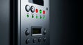 Close-up of a modern metallic control panel with digital display screen and colored buttons on a black wall Royalty Free Stock Photo