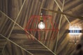 Close-up of a modern, red color copper lamp with bulb on wooden background