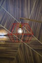 Close-up of a modern, red color copper lamp with bulb on wooden background