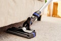 Close up of modern vacuum cleaner on beige carpet on floor in living room, copy space. Housework, household, spring-cleanig.