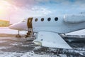 Close-up of the modern white private jet with an opened gangway door at the winter airport apron