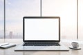 Close up of modern wooden desktop with empty white mock up laptop screen, supplies, coffee cup and panoramic window with city view Royalty Free Stock Photo