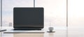 Close up of modern workspace with empty mock up laptop screen, supplies, coffee cup and panoramic window with city view in the Royalty Free Stock Photo