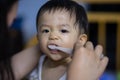 Close-up of mom hands clean the first teeth of her little baby son in the morning. Mother brushing teeth with a silicone fingertip Royalty Free Stock Photo