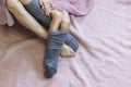 Close-up of mom legs in one sock, mother put second sock on both feet of her baby feet. Feet covered with pink blanket Royalty Free Stock Photo