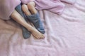 Close-up of mom s legs in one sock, mother put second sock on both feet of her baby s feet. Feet covered with pink Royalty Free Stock Photo