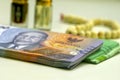 Close up of money, Indonesian rupiah banknote and perfume and prayer beads, in shallow focus