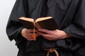 Close up of monk hands holding book and rosary . Royalty Free Stock Photo