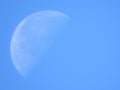 Closeup of moon with a blue daylight sky background.