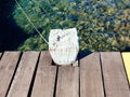 Close up of Mooring Bollard. Old wooden bollard on wooden pontoon and crystal clear water. Mooring Royalty Free Stock Photo