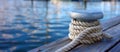 Close-up of a mooring bollard with a thick rope on a wooden dock, tranquil water behind. Royalty Free Stock Photo