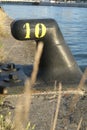 Close up of mooring noray on a dock with yellow number ten in iron.