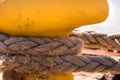 Close-up of a mooring rope with a knotted end tied around a cleat on a wooden pier Royalty Free Stock Photo